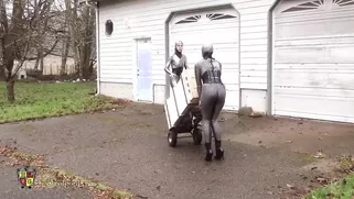 Two Babes In Tight Latex Suits Move The Box To Its Place